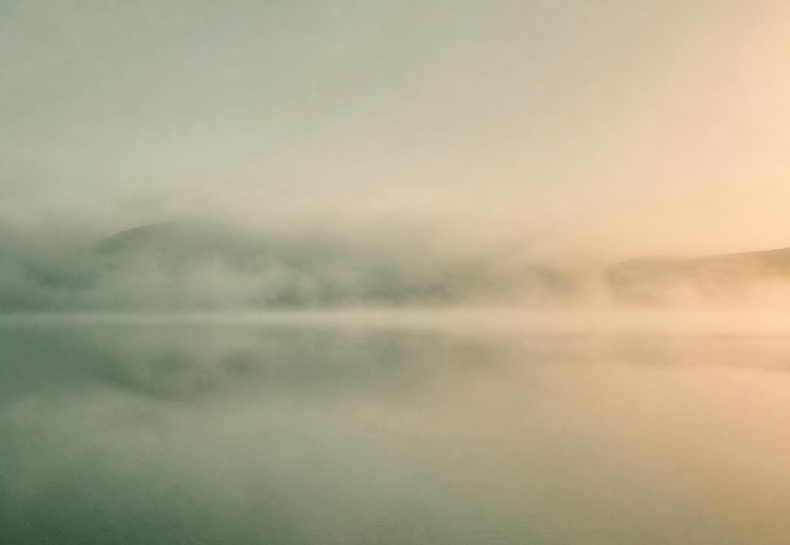 Mist drifting over still water at dawn